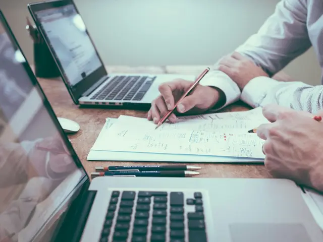 Two people reviewing printed documents together at a desk.